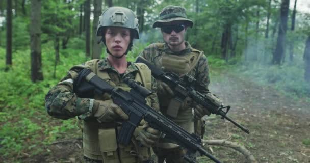 Trupp von Soldaten patrouilliert durch das Waldgebiet, Team mit männlichen und weiblichen Soldaten in dichtem Wald mit Rauch im Hintergrund — Stockvideo