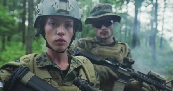 Отряд солдат, патрулирующих лесную местность, команда с солдатами мужского и женского пола в густом лесу с дымом в заднем дворе — стоковое видео