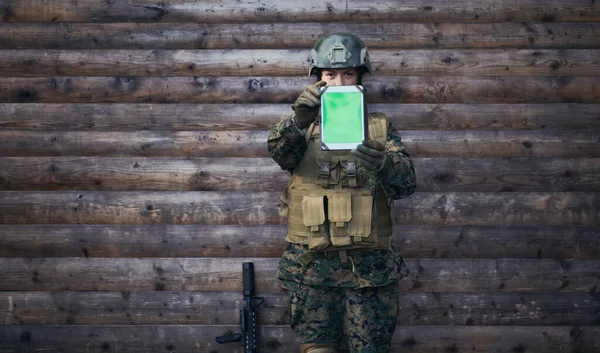 woman soldier using tablet computer  against old wooden  wall in camp