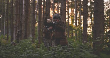 Çağdaş savaş subayı, manga ormanı çevresi için sessizce emir vermek üzere taktik el işaretleri gösteriyor.