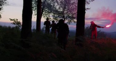 Gün batımında ormanda silahlı, askeri üniformalı iki adam.