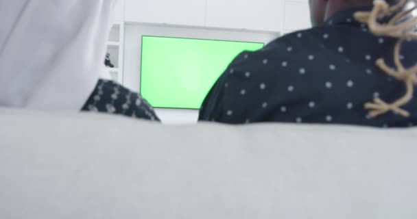 Африканская пара, сидящая на диване и смотрящая вместе телевизор — стоковое видео