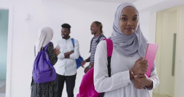 伝統的なイスラム教のヒジャーブの服を着て背景に友人のグループとアフリカの女性学生 — ストック動画