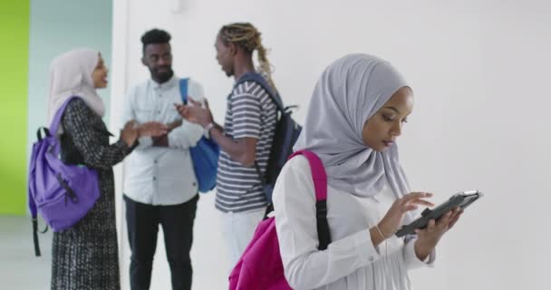 伝統的なイスラム教のヒジャーブの服を着て背景に友人のグループとアフリカの女性学生 — ストック動画