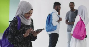 Arkaplanda arkadaş grubu olan Afrikalı kız öğrenci geleneksel İslami tesettüre bürünmüş.