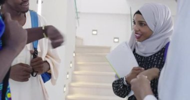 Arkaplanda arkadaş grubu olan Afrikalı kız öğrenci geleneksel İslami tesettüre bürünmüş.
