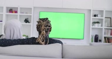 Kanepede oturup birlikte televizyon izleyen Afrikalı çift.