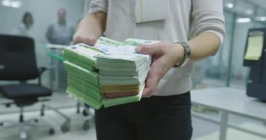 Banka çalışanları banka kasasında kağıt banknotları sıralarken ve sayarken para sayma makinesi kullanıyorlar. Bankada büyük miktarda para var.