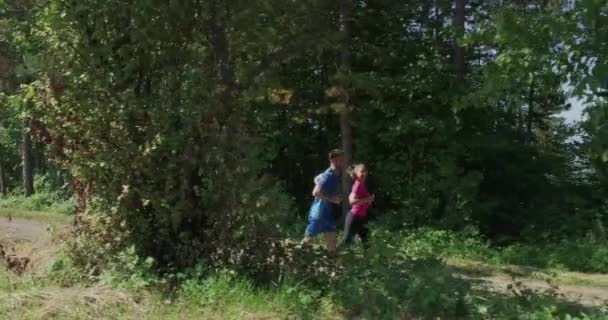 Casal correndo em uma estrada rural através da bela floresta ensolarada — Vídeo de Stock
