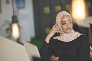 Güzel, modern, Afrikalı Müslüman iş kadını, yaratıcı, modern iş yerinde başörtüsü takıyor.