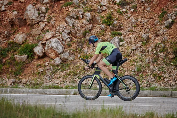 三项全能运动员骑职业自行车在弯曲的乡间路上锻炼 — 图库照片