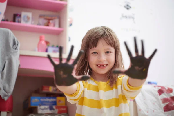 Мила маленька дівчинка вдома малює руками — стокове фото