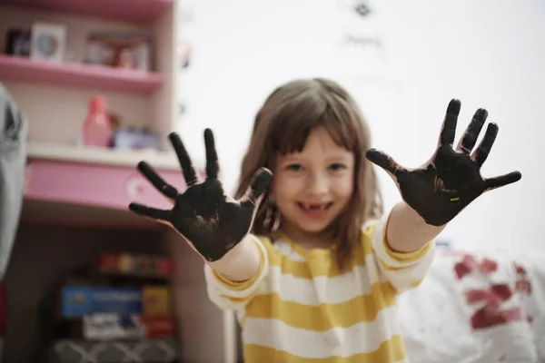Мила маленька дівчинка вдома малює руками — стокове фото
