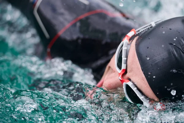 triathlon athlete swimming on lake wearing wetsuit