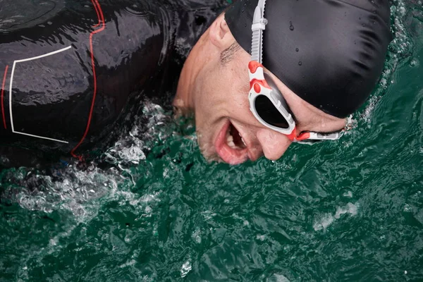 triathlon athlete swimming on lake wearing wetsuit