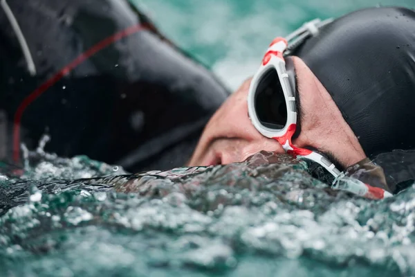 triathlon athlete swimming on lake wearing wetsuit