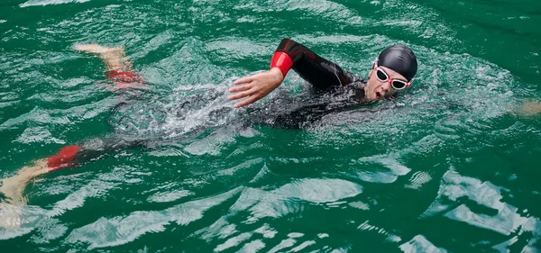Triatlon atleet zwemmen op meer dragen wetsuit — Stockfoto