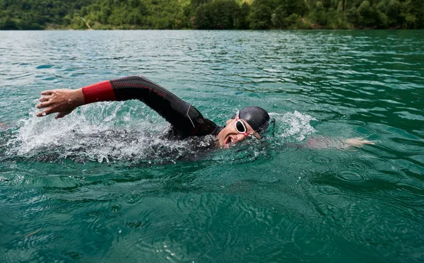 Atleta di triathlon che nuota sul lago indossando muta — Foto Stock
