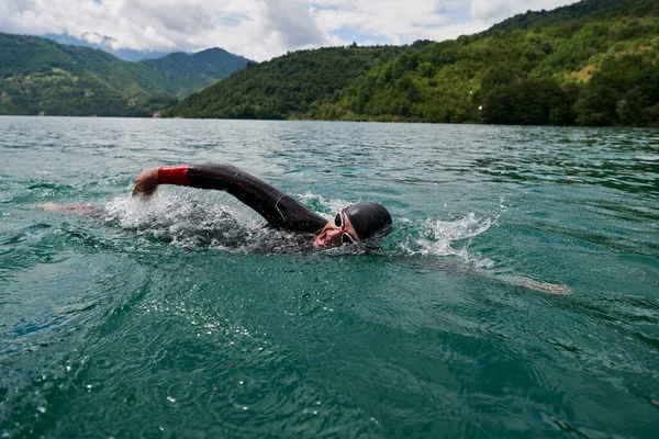 Triatlon atleet zwemmen op meer dragen wetsuit — Stockfoto