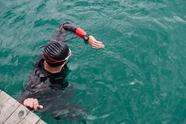 Triathlon athlete swimming on lake setting smartwatch — Stock Photo, Image