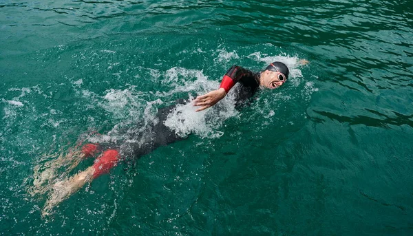 Triatlon atléta úszás a tavon búvárruhában — Stock Fotó