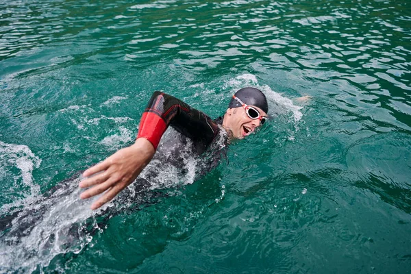 triathlon athlete swimming on lake wearing wetsuit