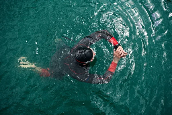 Atleta triatlo nadando no lago configuração smartwatch — Fotografia de Stock