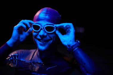 Otantik triatlet yüzücüsü gece güneşli jel üzerinde çalışırken mola veriyor.