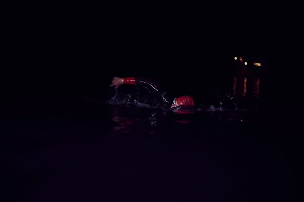 Atleta triatlo nadando na noite escura vestindo roupa de mergulho — Fotografia de Stock