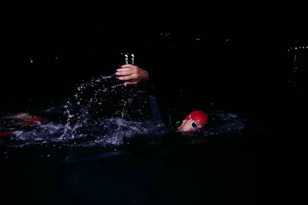 Triathlon athlete swimming in dark night wearing wetsuit — Stock Photo, Image