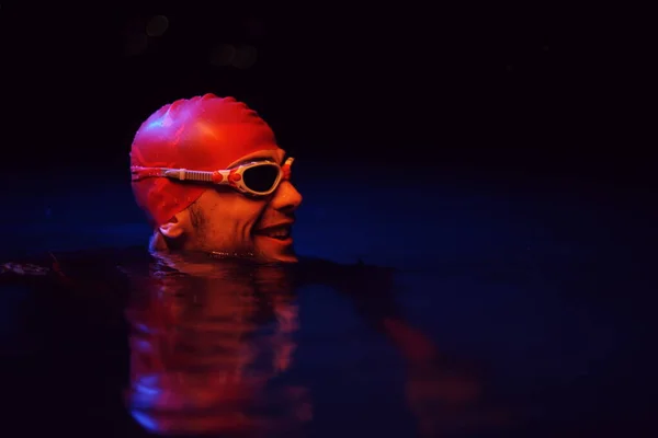 진짜 수영 선수가 밤에 네온 겔 빛에서 힘든 훈련을 받는 동안 휴식을 취하는 모습 — 스톡 사진