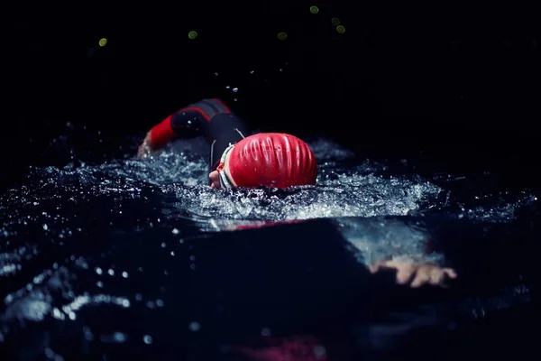 Triatlon atleet zwemmen in donkere nacht in wetsuit — Stockfoto