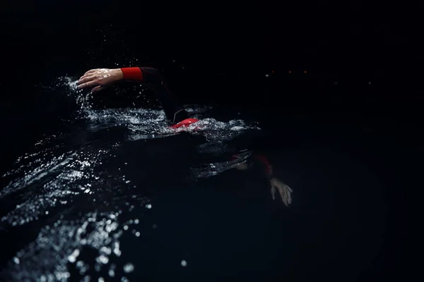 Atleta triatlo nadando na noite escura vestindo roupa de mergulho — Fotografia de Stock