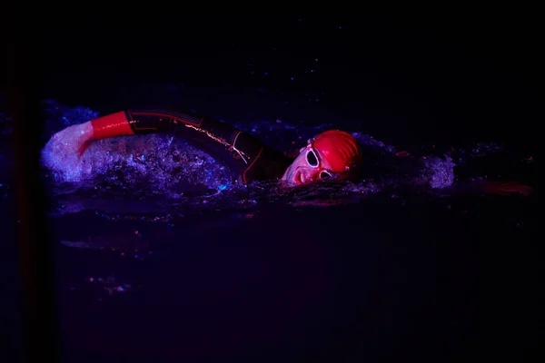 Настоящий атлет-триатлон, плавающий в темноте ночи — стоковое фото