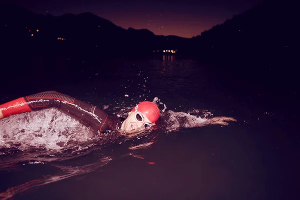 어두운 밤에 잠수복을 입고 수영하는 트라이애슬론 선수 — 스톡 사진