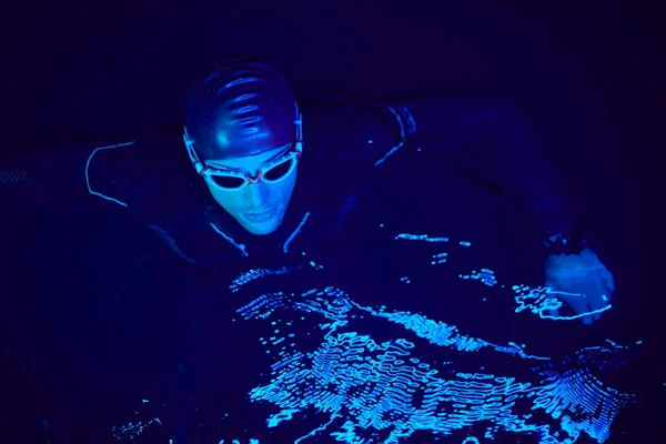 Autentikus triatlonos úszó, aki szünet alatt kemény edzés éjszakai neon gél fény — Stock Fotó