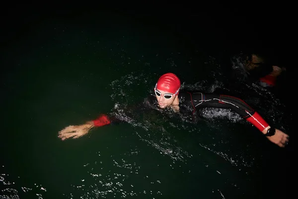 Atleta de triatlón nadando en la noche oscura usando traje de neopreno —  Fotos de Stock