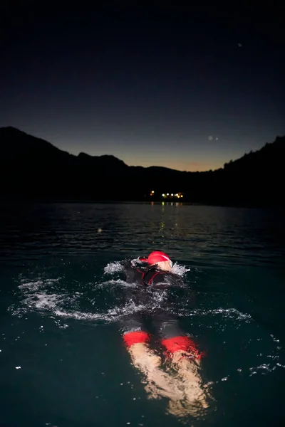 Triatlon atleet zwemmen in donkere nacht in wetsuit — Stockfoto