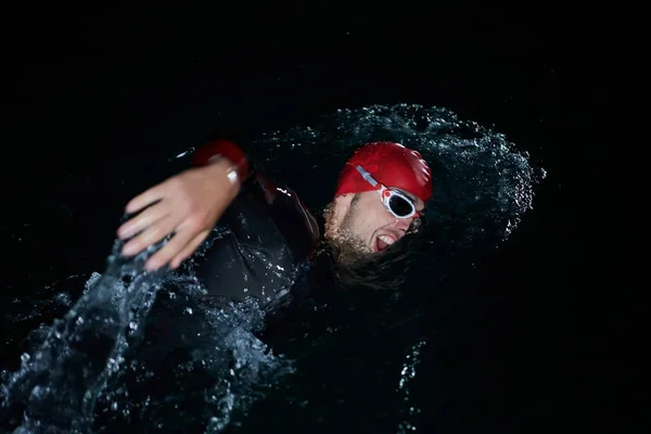 Atleta de triatlón nadando en la noche oscura usando traje de neopreno —  Fotos de Stock
