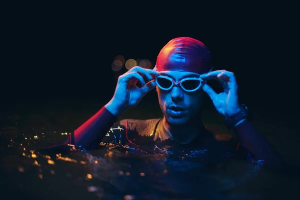 Autentico nuotatore triatleta che ha una pausa durante il duro allenamento sulla luce al neon gel notte — Foto Stock