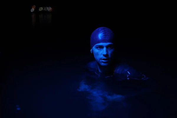 Автентичний тріатлоніст плавець має перерву під час важкої підготовки на нічному неоновому гелевому світлі — стокове фото