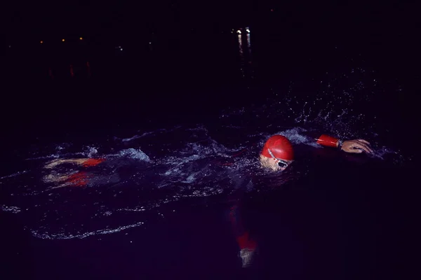 Atleta triatlo nadando na noite escura vestindo roupa de mergulho — Fotografia de Stock