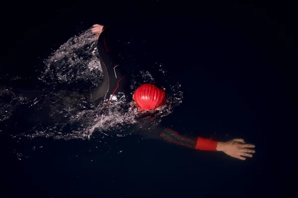 어두운 밤에 잠수복을 입고 수영하는 트라이애슬론 선수 — 스톡 사진