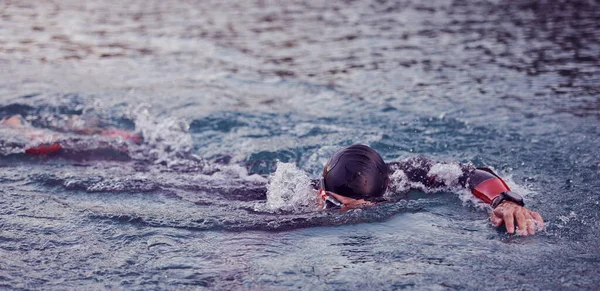 Atleta triatlo nadando no lago ao nascer do sol vestindo roupa de mergulho — Fotografia de Stock