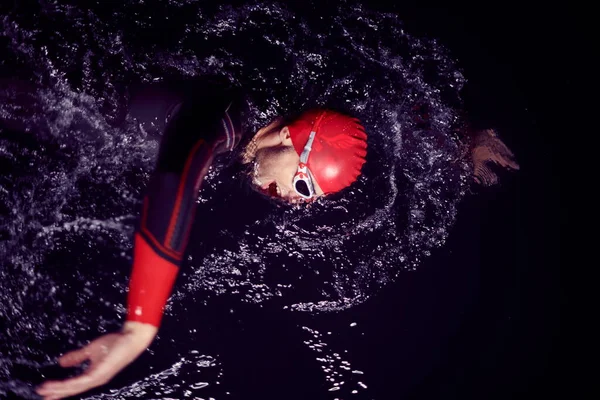 Triathlon athlete swimming in dark night wearing wetsuit — Stock Photo, Image