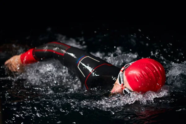 Triatlon atléta úszás sötét éjszaka visel búvárruha — Stock Fotó
