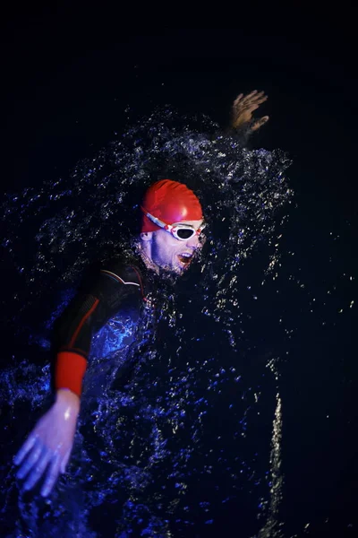 Atleta de triatlón real nadando en la noche oscura — Foto de Stock