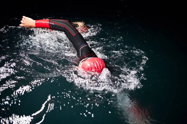 Atleta de triatlón nadando en la noche oscura usando traje de neopreno —  Fotos de Stock