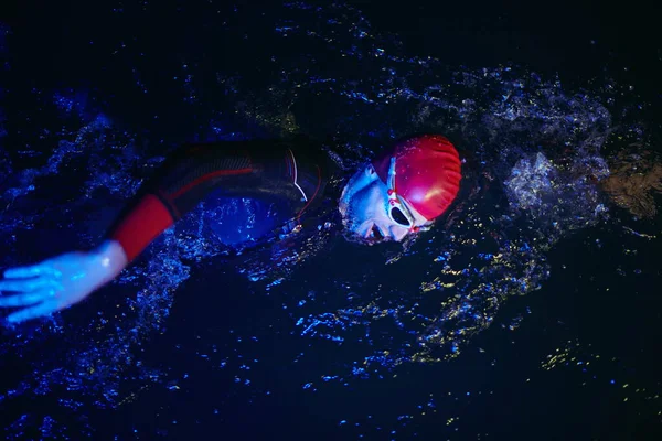 Настоящий атлет-триатлон, плавающий в темноте ночи — стоковое фото