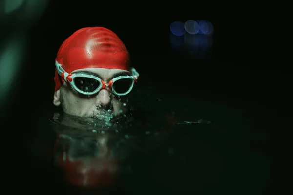 Autentisk triathlete simmare som har en paus under hård träning på natten neon gel ljus — Stockfoto